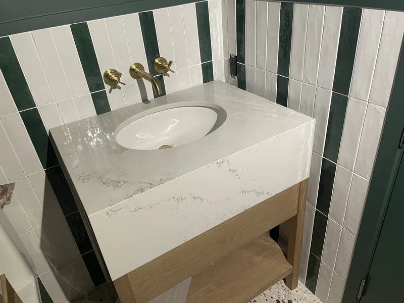 Thick-front white vanity against green wall tile