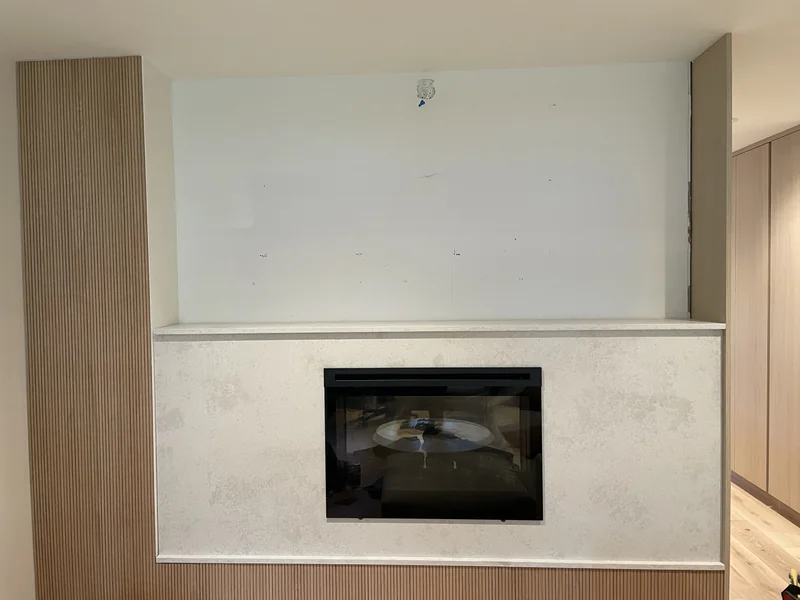 Light fireplace surround framed by fluted wood