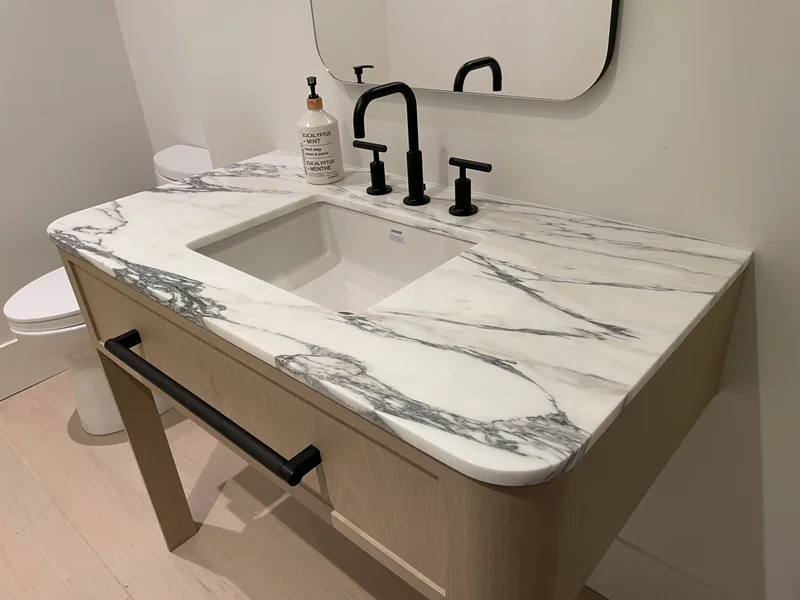 Rounded vanity corner beside matte black fittings